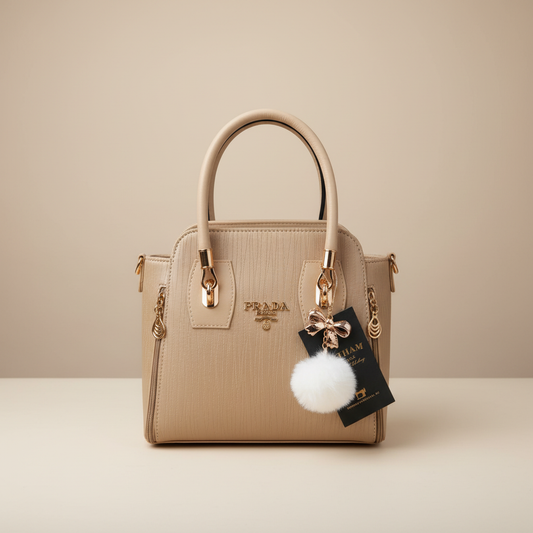Elegant beige ladies handbag with gold hardware and pom pom charm
