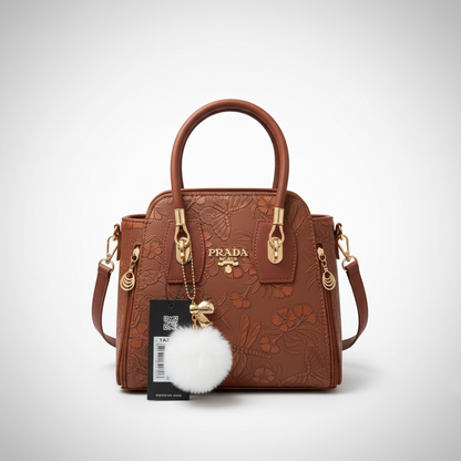 Elegant brown ladies handbag with floral embossed design and pom pom charm
